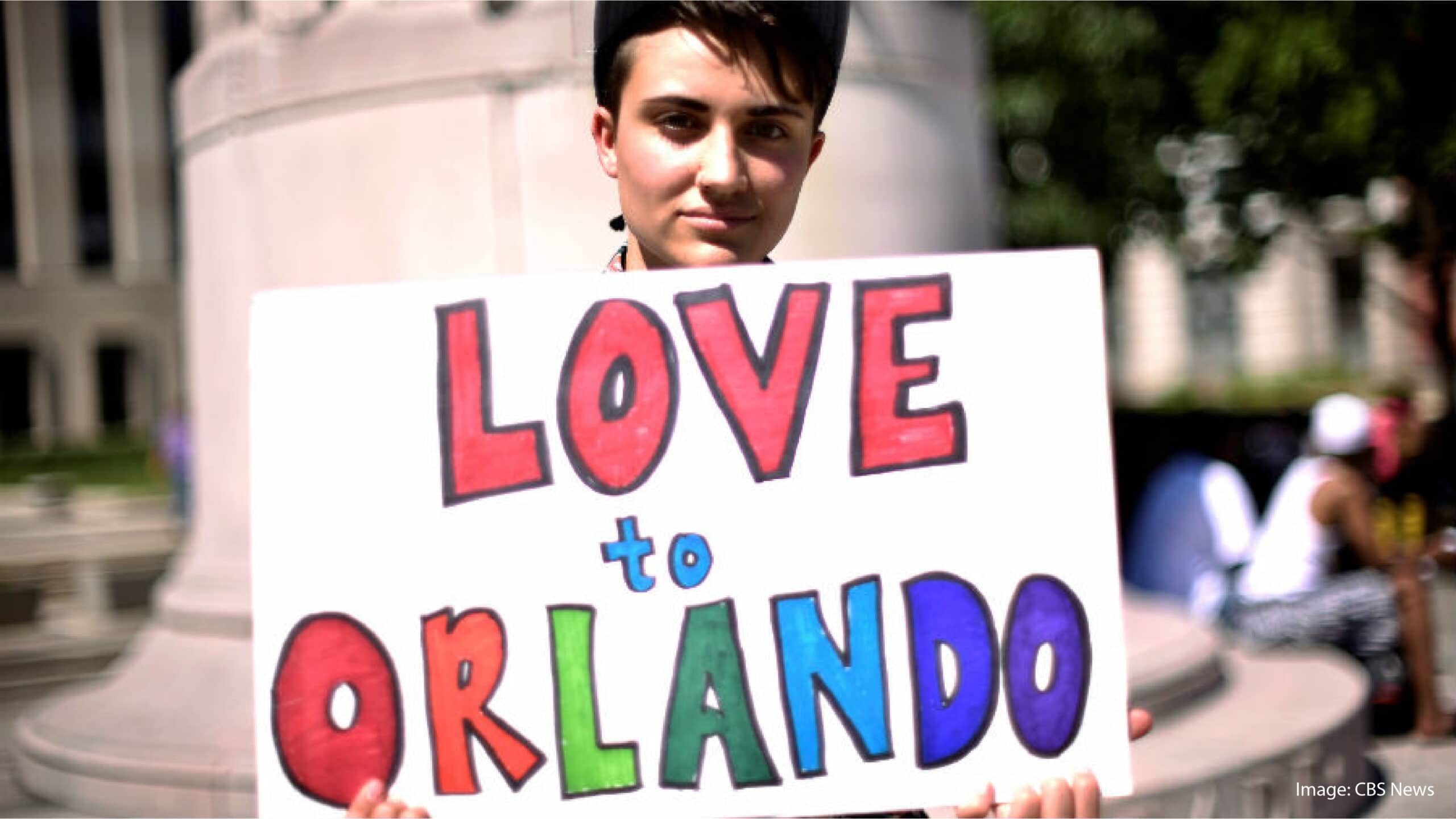 Man holding a sign that says "Love to Orlando"